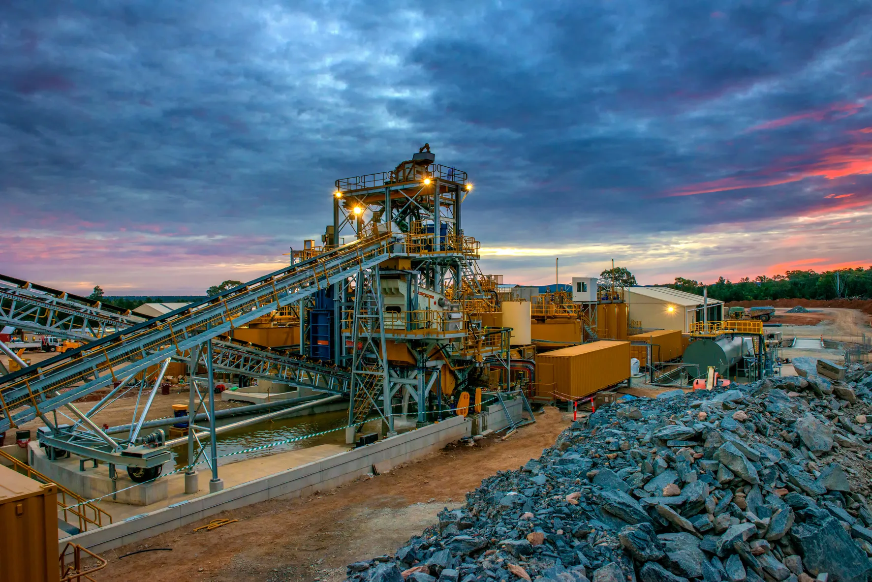 Planta de procesamiento minero con correas transportadoras al atardecer